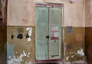 An old gree door leading to headquarters in Ruined Military Base escape game.